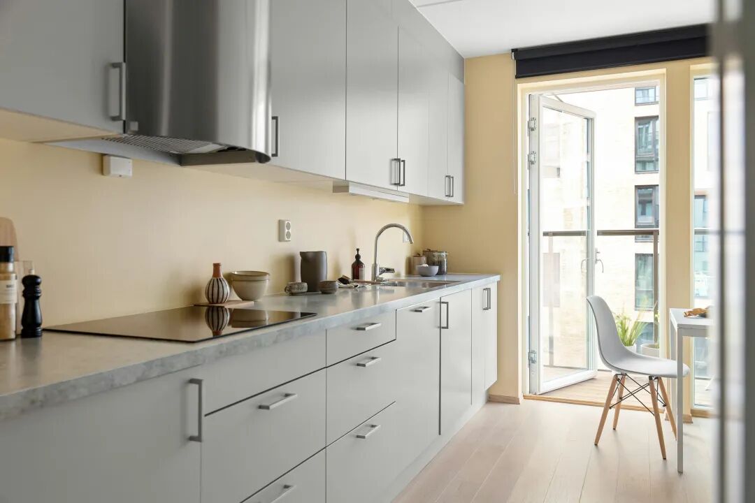 A kitchen with white cabinets and a wooden floor