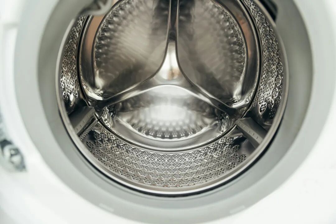 Inside view of a clean, empty washing machine drum.